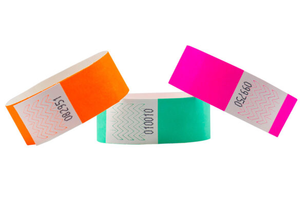 Set of 25mm Tyvek wristbands in orange, green, and pink. Detail view of serial numbering and adhesive zone. Manufacturer AMGS Group.